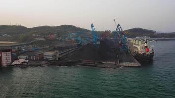 Drone view of cranes loading coal in the port on a bulk carrier video