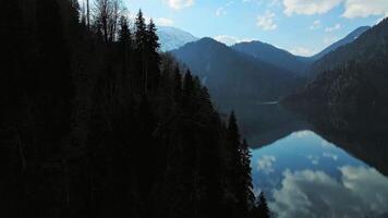 Clear blue mountain lake with reflection of clouds on the water. Drone view video
