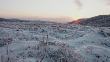 Close-up view from a drone to the ground covered with ice and bridge at sunset. video