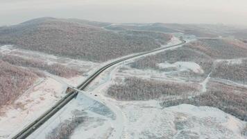 Drone approach to the road with traffic among the hills in winter video