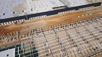 Construction site with steel frame structure of warehouse building, aerial view video