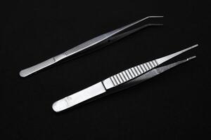 Metal tweezers for work. Tweezers for electronics on a black background. photo
