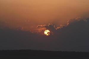 The solar disk. The setting sun in a cloud over the forest. photo
