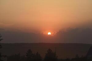 The solar disk. The setting sun in a cloud over the forest. photo
