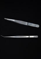 Metal tweezers for work. Tweezers for electronics on a black background. photo