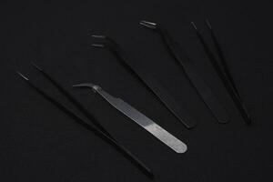 Metal tweezers for work. Tweezers for electronics on a black background. photo