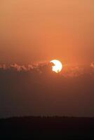 The solar disk. The setting sun in a cloud over the forest. photo