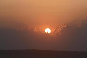 The solar disk. The setting sun in a cloud over the forest. photo