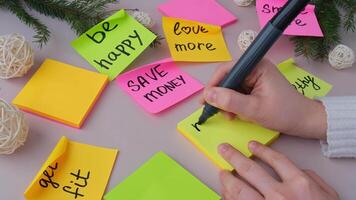 Woman writing promises and aims. MORE FAMILY TIME text Preparation for new year new life new me. Visualizing wish list for 2025. Dreams plan action resolutions for coming year. Inspirational self improvement concept video
