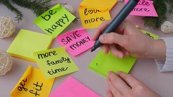 Female hands writing 2025 GOALS handwritten new year resolutions aims goals on sticky notes. Preparation for New Year. Concept of planning and setting goals for personal development video