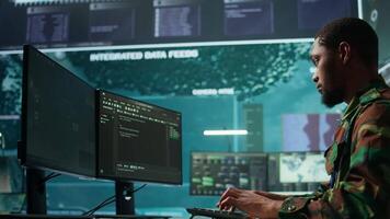 IT expert monitors AI brain intelligence system to collect crucial real time data for a new defense military operation on pc in command post. Security protocols for an intense mission. Camera B. video