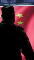 Vertical Chinese military officer analyzing information on big screen in a command center base of operations. Chinese flag running on display while soldiers inflict fear through fake news, national security. Camera A. video