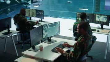 Military personnel in a high tech command center monitor satellite feeds, coordinate intelligence operations. Maintaining national security and supporting strategic army missions. Camera B. video