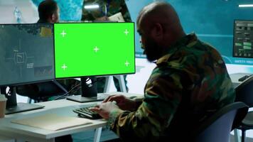 Soldier analyzing real time data next to green screen in high tech military office, processing intelligence for field operations and coordinating strategic missions to ensure national interests. Camera A. video