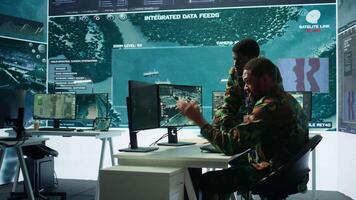 Government analysts work in an advanced command center with satellite radar systems, overseeing surveillance activities and interpreting real time data. Protecting national interests. Camera B. video