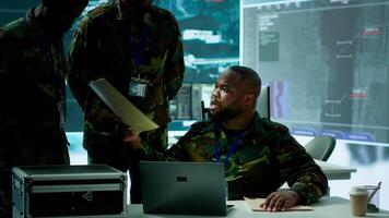 Military personnel in a modern command center handle critical information, collecting live surveillance data to maintain security protocols. Team of army crew working on reconnaissance. Camera A. video