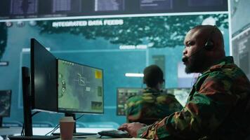 Government intelligence officer in high tech command post oversee satellite data, real time surveillance footage via radar cctv and coordinate operations. Protecting national interests. Camera B. video