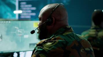 Government intelligence officer in high tech command post oversee satellite data, real time surveillance footage via radar cctv and coordinate operations. Protecting national interests. Camera A. video