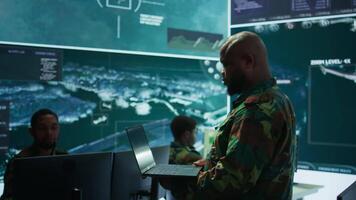 Cybersecurity team operates in an advanced military command center, surveillance systems and data protection. Army personnel work on national security operations using high tech gear. Camera B. video