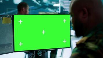 Army officer gathers intelligence from radar next to isolated copy space, working on satellite data monitoring from control room. Employs high tech gear and big screen in command post. Camera A. video
