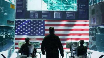 US military officer supervising threat detection activity in high tech office, examining top secret data on big screen. American army soldiers managing hybrid war, cyber attack prevention. Camera B. video