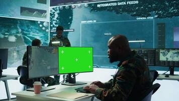 Soldier analyzing real time data next to green screen in high tech military office, processing intelligence for field operations and coordinating strategic missions to ensure national interests. Camera B. video