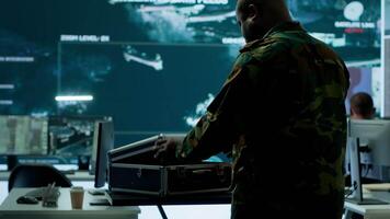 Army espionage specialist in a control center collecting satellite cctv data real time surveillance, strategic military operations. Working to ensure national security and protocols. Camera A. video