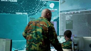 Military team operating in a high tech command post control tower, focusing on surveillance tactics for intelligence gathering. Data protection to manage critical information operations. Camera A. video