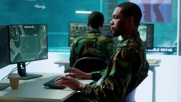 Military personnel in a high tech command center monitor satellite feeds, coordinate intelligence operations. Maintaining national security and supporting strategic army missions. Camera A. video