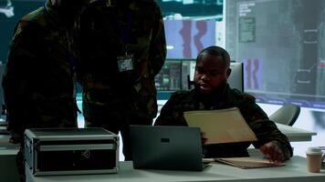 In a high tech military office, soldiers team analyze real time data collected by surveillance system. Staff interpret intelligence and coordinate operations to ensure national defense. Camera A. video