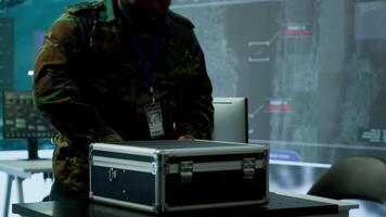 Military expert in a control center uses advanced technology and gear to gather intelligence from satellite imagery and surveillance systems. Using laptop to communicate information. Camera A. video