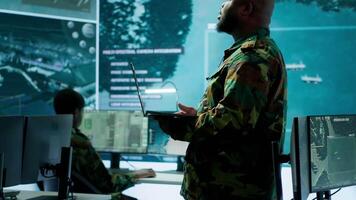 Military team manages cybersecurity operations in a high tech control center base of operations, managing data protection and surveillance systems, safeguarding national security. Camera A. video