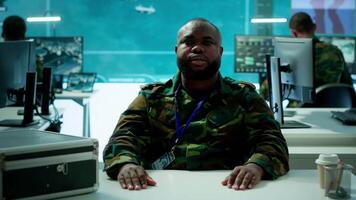 Military officer participates in a secure videoconference call in modern command center, transmitting live satellite information. Federal collaboration for national security operations. Camera A. video