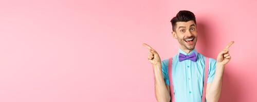 Handsome funny guy pointing fingers aside, showing left and right logo and smiling, recommending two choices, standing on pink background photo