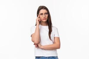 Waist-up portrait of doubtful attractive brunette girl looking focused and suspicious, thinking squinting and looking away while processing information with disbelief and doubt, white background photo