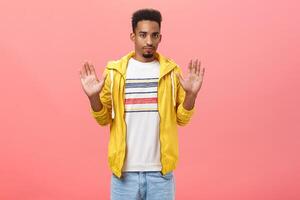 Man feeling intense not liking bad idea of friend rejecting in participating suspicious deal raising palms in refusal gesture staring concerned and displeased at camera over pink background photo
