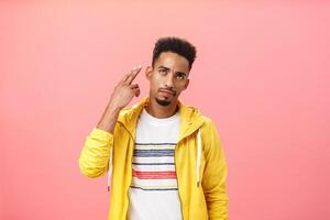 You kill my vibe. Gloomy irritated and annoyed handsome stylish african american guy in yellow trendy jacket showing finger gun gesture over temple as if shooting himself with bothered look photo