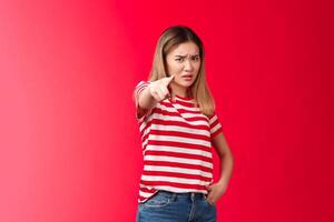Girl plead you guilty. Upset asian blond girlfriend being cheated on pointing camera blame person make accusations, frowning disappointed and hurt, stand red background bothered offended photo