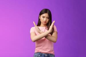 Serious-looking annoyed fed up asian girl demand stop, make arm cross chest forbidden gesture, look with scorn and disappointment, refusing terrible offer, give rejection, wanna end argument photo