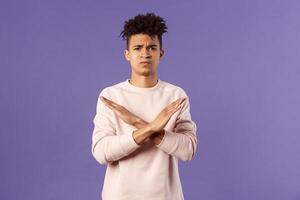 Portrait of young fed up man express his strong will to end this relationship, cross hands over chest in stop, enough gesture pouting and frowning, looking serious, disagree and prohibit action photo
