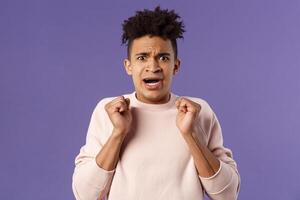 Close-up portrait of worried, anxious funny hispanic man jumping from fear, gasping look concerned, starting to panic before important meeting, standing purple background afraid and nervous photo