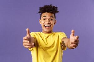Close-up portrait of charismatic, happy friendly-looking hispanic man with dreads reaching hands forward to hold something, give hug or cuddle dearly, standing purple background photo