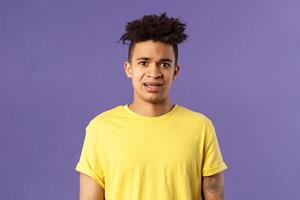 Waist-up portrait of young concerned hispanic man with worried gaze looking at camera, frowning being scared for friend stuck in troublesome situation, want help, stand purple background photo