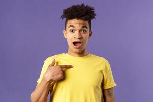 Who me, no way. Portrait of surprised, happy rejoicing young man looking with disbelies as being chosen from all candidates, pointing at himself open mouth fascinated, purple background photo