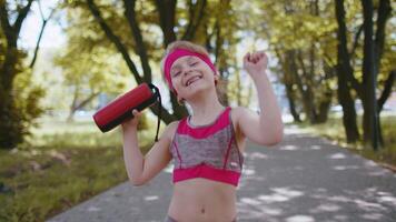 Sport runner jogger child girl listen bluetooth music speaker dancing having fun walking in park video