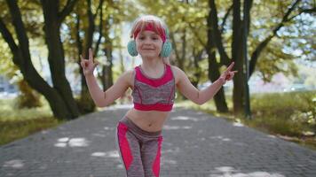 Sport runner child girl training exercise listening music on headphones dancing to camera having fun video