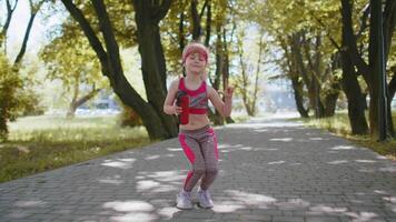 Sport runner jogger child girl listen bluetooth music speaker dancing to camera having fun in park video