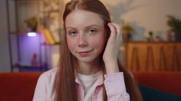 Close-up of happy beautiful young redhead child girl smiling looking at camera at home on couch video