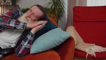 Tired one senior old man lying down in bed taking a rest at home, napping, falling asleep on sofa video