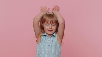 Lovely funny comical child girl kid smiling friendly and doing bunny ears gesture on head, fooling video